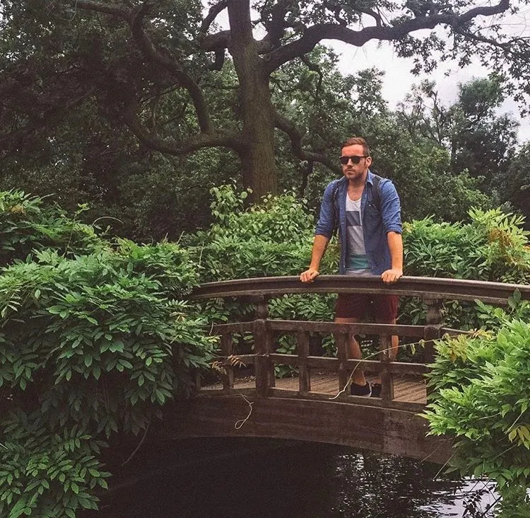 Steven of the Anxious Adventurer poses for a picture on a bridge in the woods on an international travel trip