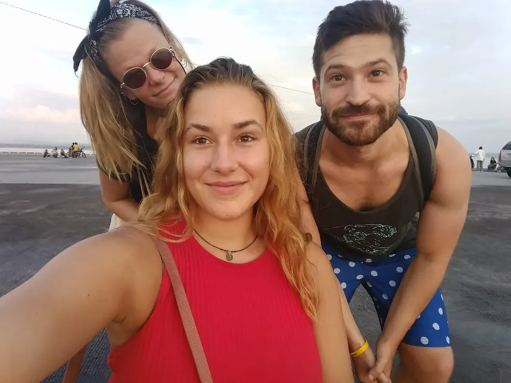Three travelers, one male traveler and two female travelers pose for a picture at sunset in Legazpi, Philippines