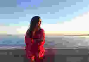 a female traveler in a red dress on the coast posing for a photo