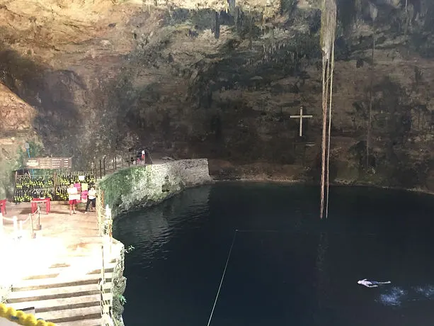 a cenote in Mexico's Yucatan Peninsula with a cross in the background