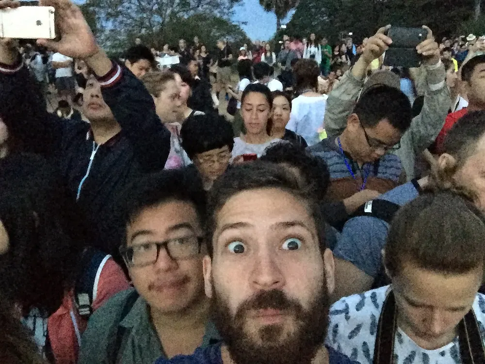 Two traveler friends taking a selfie at a crowded sunrise in the Angkor Wat
