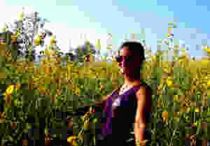 a female solo traveler posing for a picture in front of a field of sun flowers