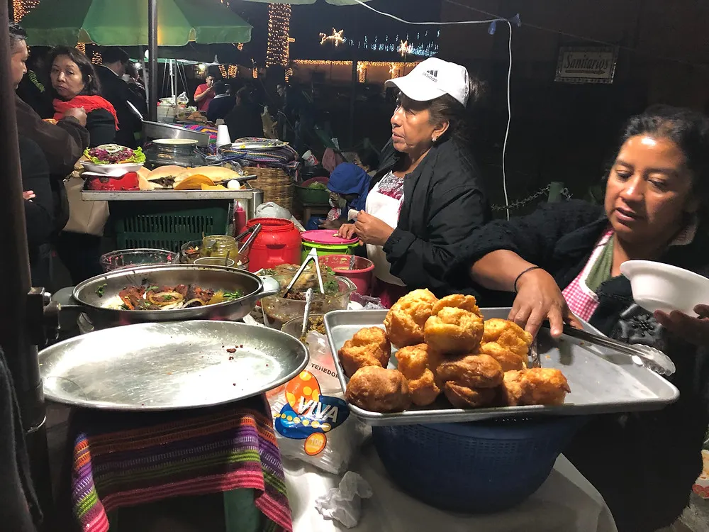 an evening market stand in Antigua, Guatemala where women are selling sweetened fried dough on the street