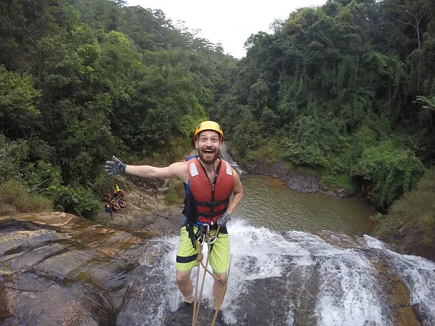 a male traveler poses during a canyoning trip in Dalat Vietnam before climbing down a waterfall