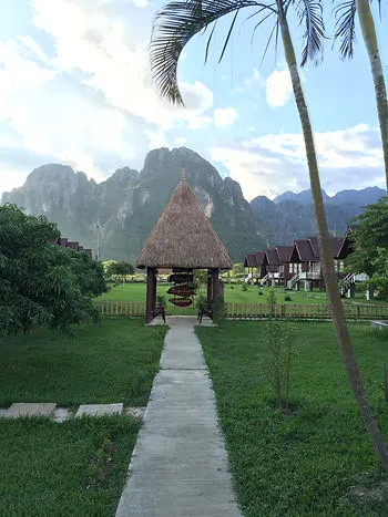 a view of the limestone cliffs and thatched roof homes in Vang Vieng, Laos