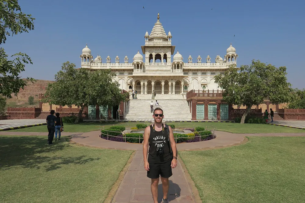 Steven of The Anxious Adventurer poses for a picture in front of a beautiful white palace while traveling and backpacking internationally