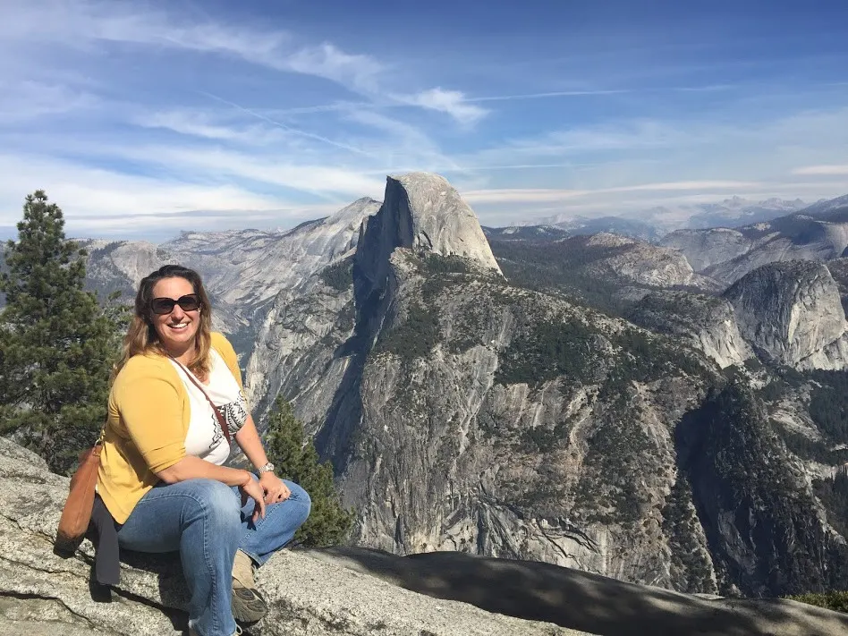 Meredith from Beautiful Voyager posing for a picture in Yosemite National Park in California overlooking mountains and forests