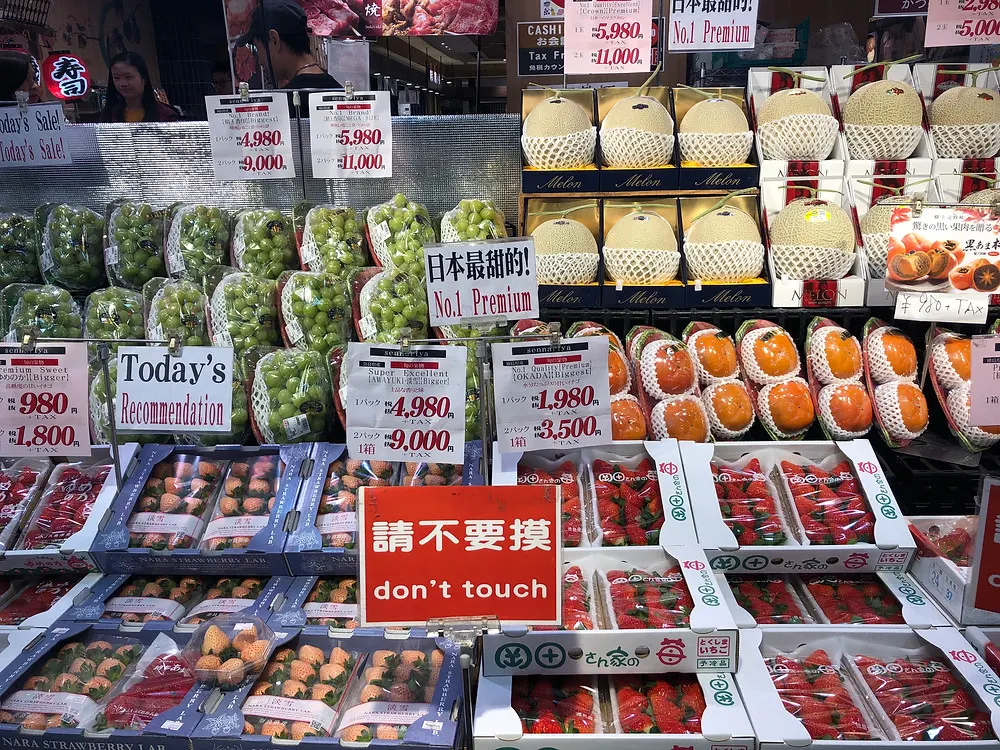 A fruit stand in Kyoto's public market in Japan with melons, grapes, strawberries and persimmons
