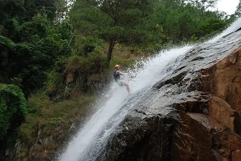 a traveler doing the canyoning tour climbing down a waterfall in Dalat Vietnam
