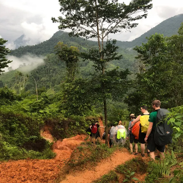 A group of hikers descend an orange dirt path in Colombia's Lost City Trek in the Santa Marta region