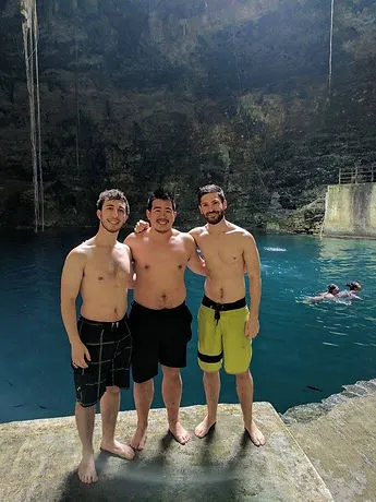 three male travelers posing for a picture in a cenote i Mexico's Yucatan Peninsula